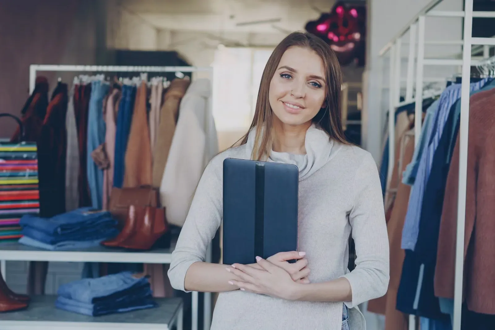 A clothing boutique owner holding a tablet in her shop